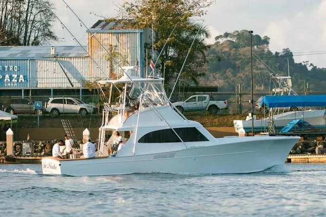 Sportfishing charter boat with tower and outriggers cruising past Marina Pez Vela in Quepos, Costa Rica