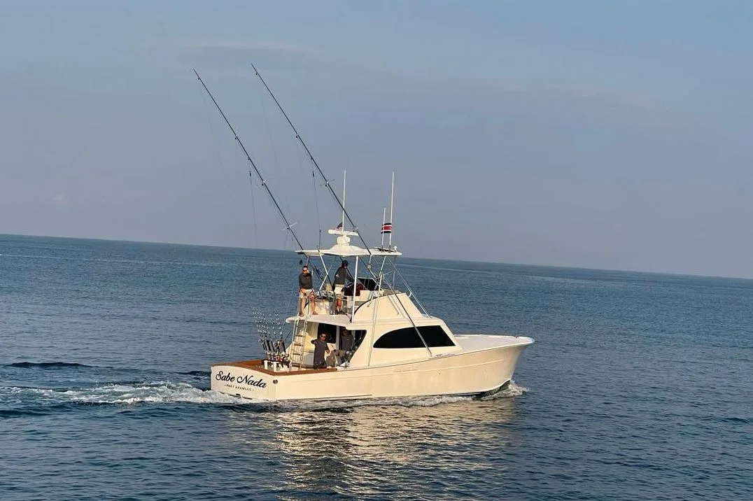 Sportfishing boat with crew on the tower and rods out running over calm Pacific water off Costa Rica